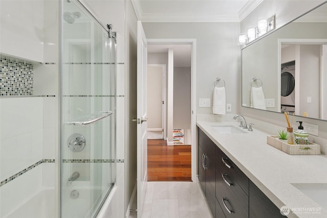 bathroom with double vanity, a sink, ornamental molding, and stacked washer and dryer