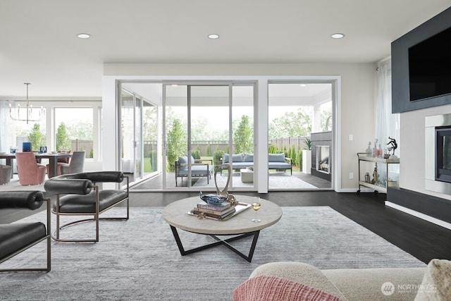 living area with a wealth of natural light, recessed lighting, a glass covered fireplace, and dark wood-style flooring