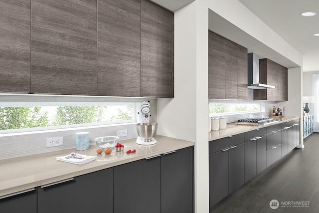 kitchen with light countertops, wall chimney range hood, modern cabinets, and stainless steel gas cooktop