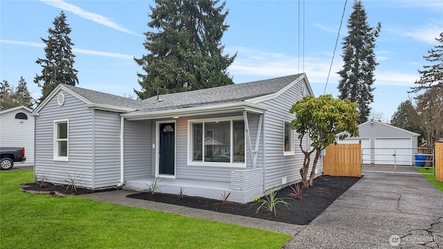 view of front of home with a front yard, a gate, fence, an outdoor structure, and a detached garage