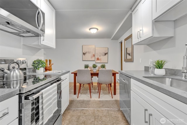 kitchen featuring light tile patterned floors, stainless steel appliances, light countertops, white cabinets, and light carpet