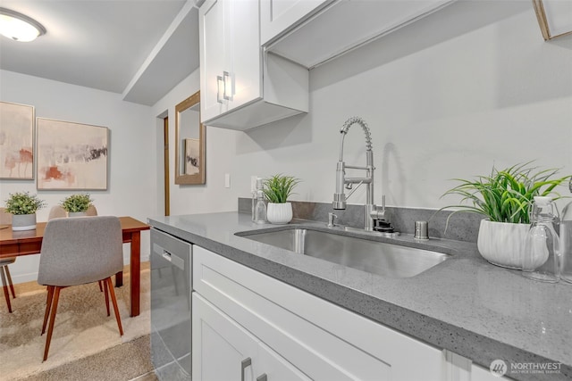 kitchen featuring dark stone countertops, white cabinets, dishwasher, and a sink