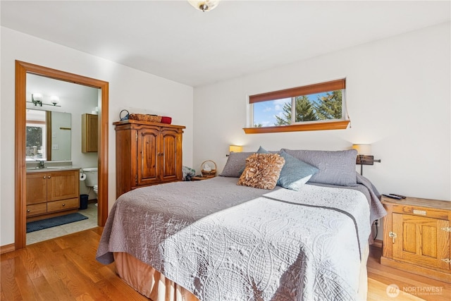 bedroom with wood finished floors, ensuite bathroom, and a sink