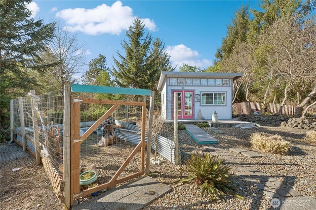 view of outbuilding with an outdoor structure, fence, and french doors