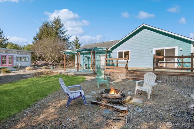 rear view of property with a lawn, french doors, an outdoor fire pit, and a deck