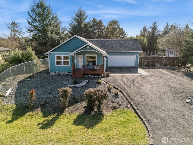 view of front of home with a front yard, fence, gravel driveway, a porch, and a garage