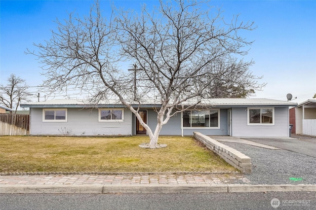 ranch-style house featuring a front yard, fence, and metal roof