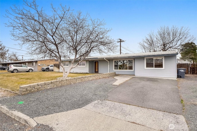 ranch-style house with a front lawn, fence, aphalt driveway, and metal roof