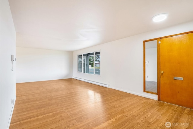 empty room featuring a baseboard heating unit and light wood-style floors