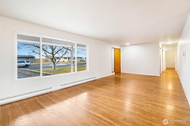 spare room featuring light wood finished floors, baseboards, and a baseboard radiator