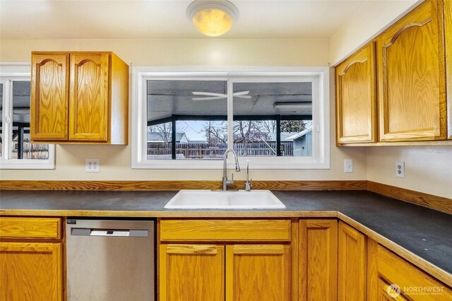 kitchen featuring dark countertops, dishwasher, brown cabinetry, and a sink