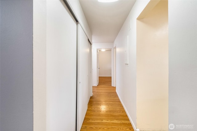 hall with light wood-style flooring and baseboards