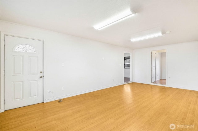 spare room featuring baseboards and light wood finished floors