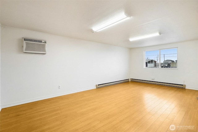 spare room featuring baseboards, baseboard heating, wood finished floors, and a wall mounted AC