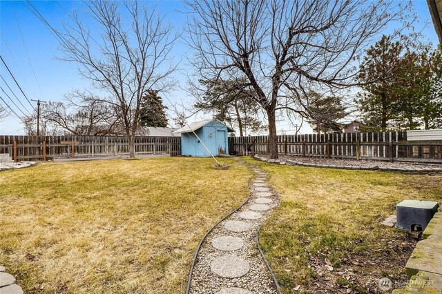 view of yard with an outbuilding, a storage unit, and a fenced backyard