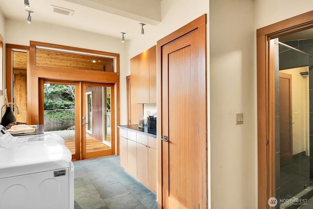 interior space with washing machine and clothes dryer, visible vents, modern cabinets, and dark countertops