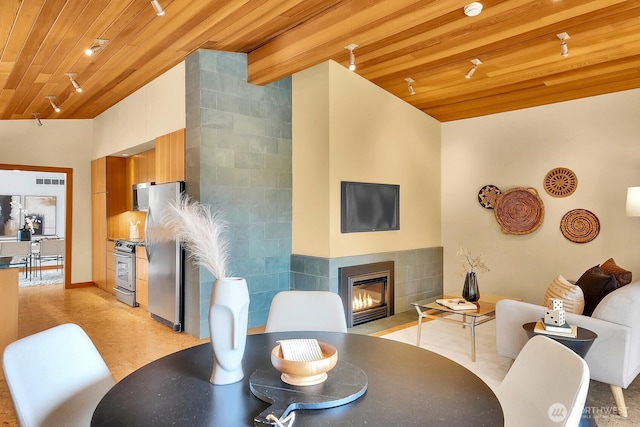 dining room featuring vaulted ceiling with beams, wood ceiling, and a fireplace