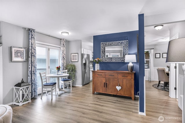 interior space with light wood-style floors, stainless steel fridge, and baseboards