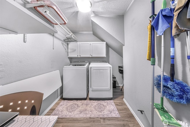 laundry area with cabinet space, wood finished floors, a textured wall, and separate washer and dryer