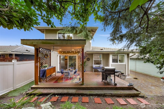 back of property with outdoor dining area, a deck, and fence