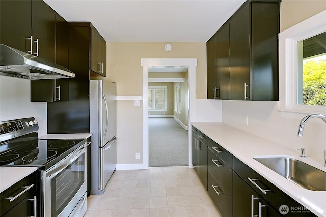 kitchen featuring under cabinet range hood, stainless steel appliances, light countertops, and a sink