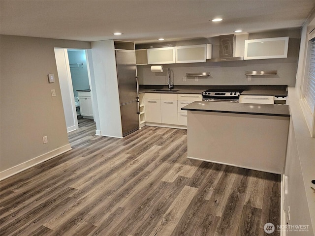 kitchen featuring a sink, dark countertops, wood finished floors, stainless steel range with electric cooktop, and baseboards