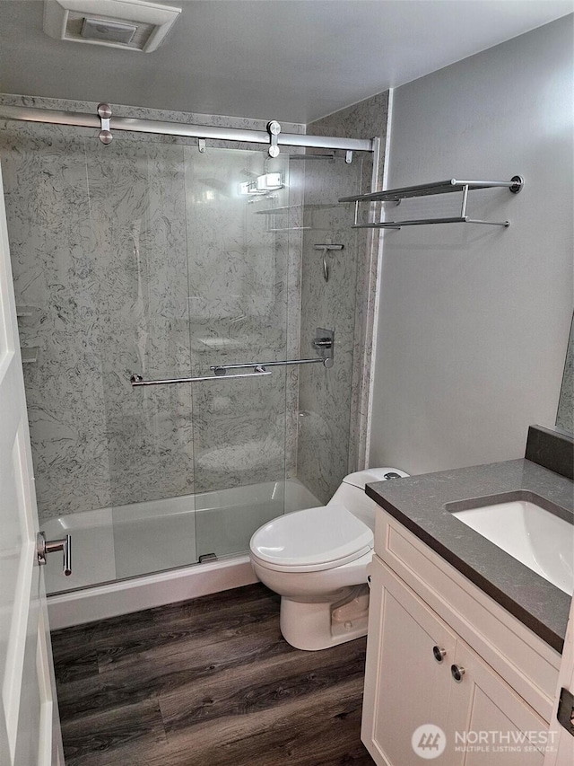 bathroom featuring visible vents, toilet, a stall shower, wood finished floors, and vanity