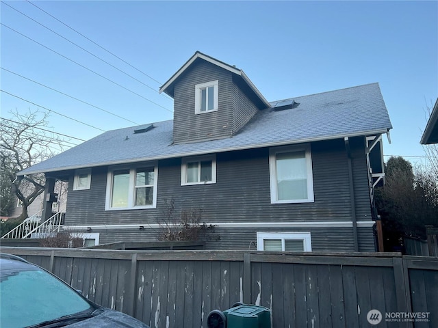 exterior space with roof with shingles, central AC, and fence