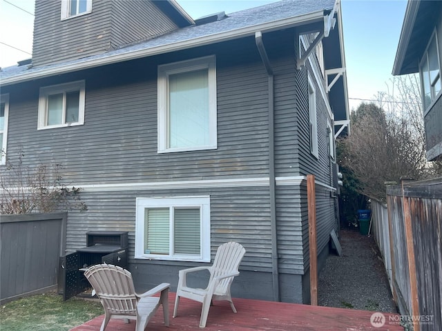 back of property with fence and a shingled roof