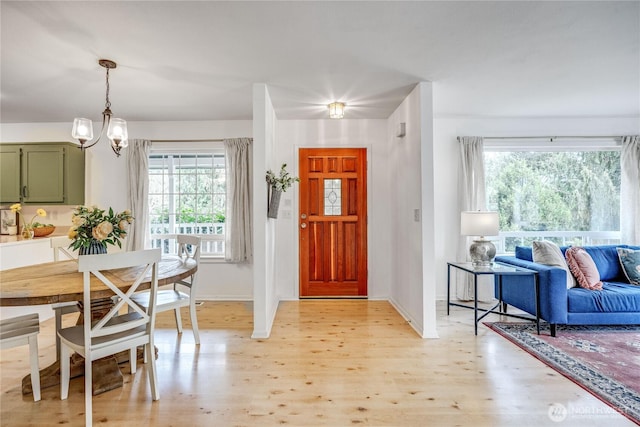 entryway featuring a chandelier, light wood-type flooring, and baseboards