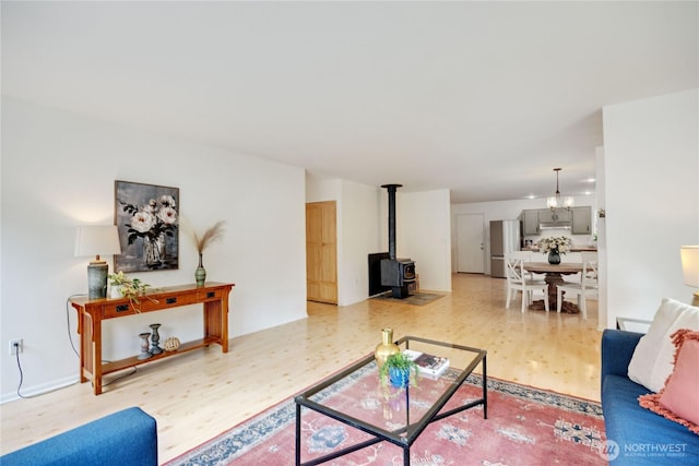 living room featuring a chandelier, light wood-style flooring, and a wood stove