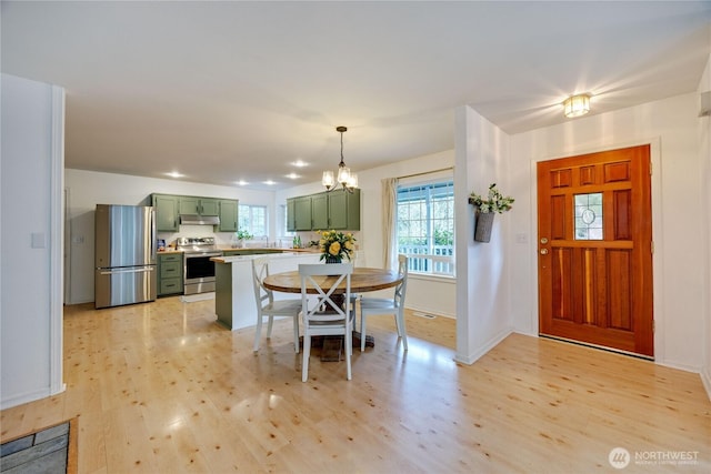 dining room featuring light wood-style flooring, baseboards, and a chandelier