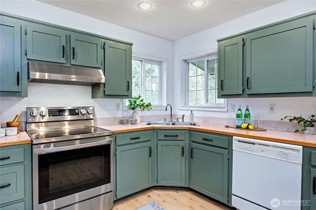 kitchen featuring a sink, under cabinet range hood, stainless steel range with electric cooktop, white dishwasher, and light countertops