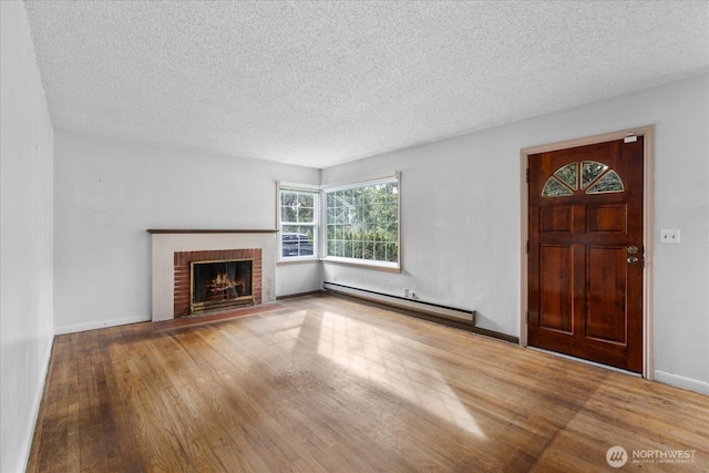 unfurnished living room with baseboards, baseboard heating, a fireplace, wood finished floors, and a textured ceiling