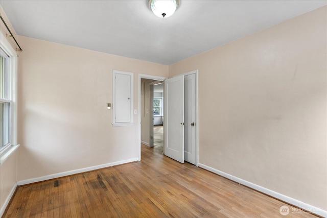 unfurnished room with baseboards and hardwood / wood-style flooring