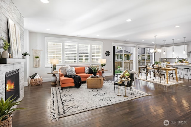 living room featuring a notable chandelier, dark wood-style floors, recessed lighting, a fireplace, and baseboards