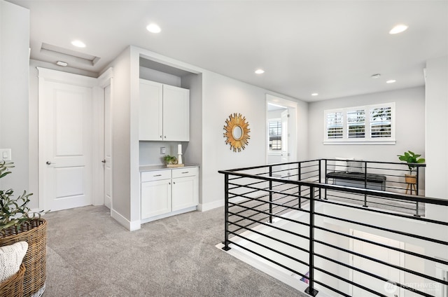 hallway featuring recessed lighting, baseboards, light carpet, and an upstairs landing