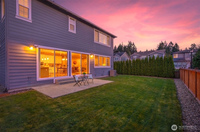 back of house at dusk featuring a yard, a patio area, central AC unit, and fence