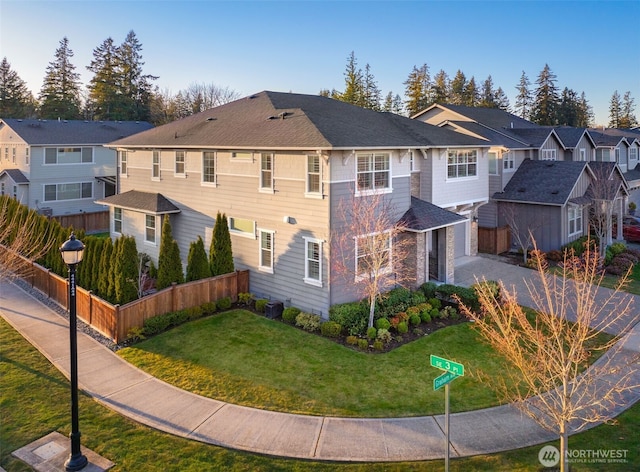 exterior space with a front yard, fence, driveway, an attached garage, and a residential view