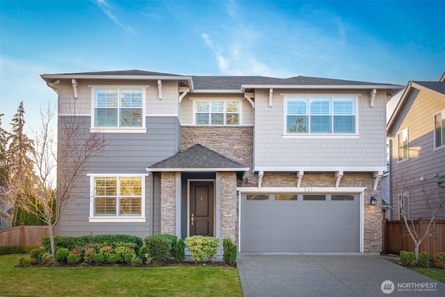 view of front of house featuring stone siding, an attached garage, driveway, and fence