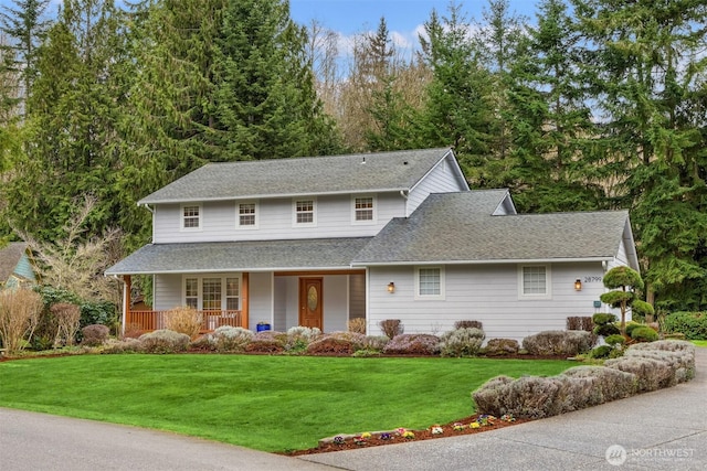 traditional home with roof with shingles, a porch, and a front lawn