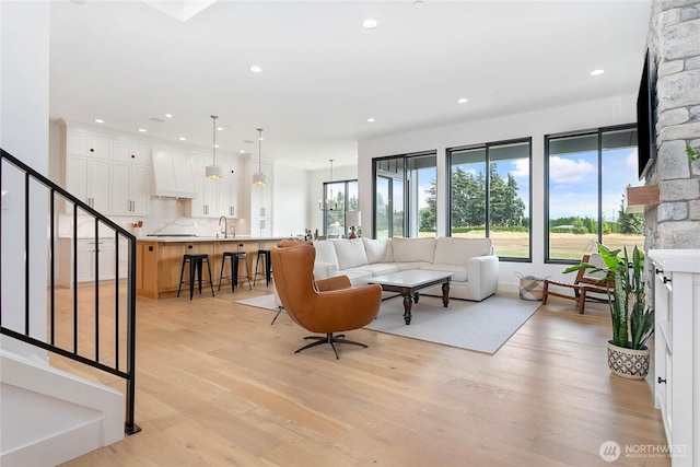 living room with stairway, recessed lighting, light wood finished floors, and a chandelier