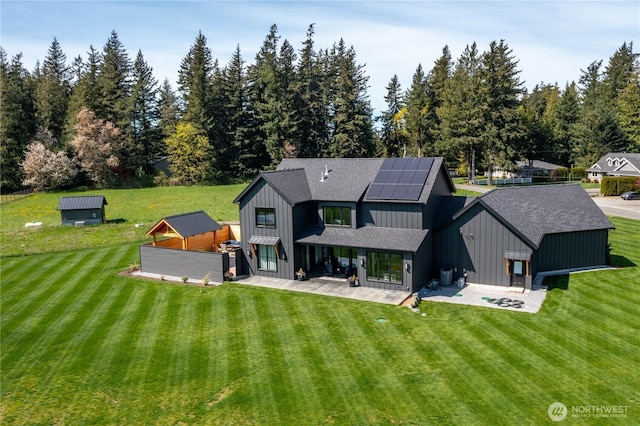 837 Van Dyk Rd, Lynden, WA 98264 - back of house with a lawn, a shingled roof, board and batten siding, an outdoor structure, and solar panels