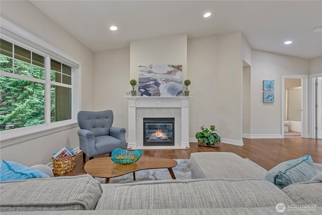 living room with a fireplace, recessed lighting, wood finished floors, and baseboards