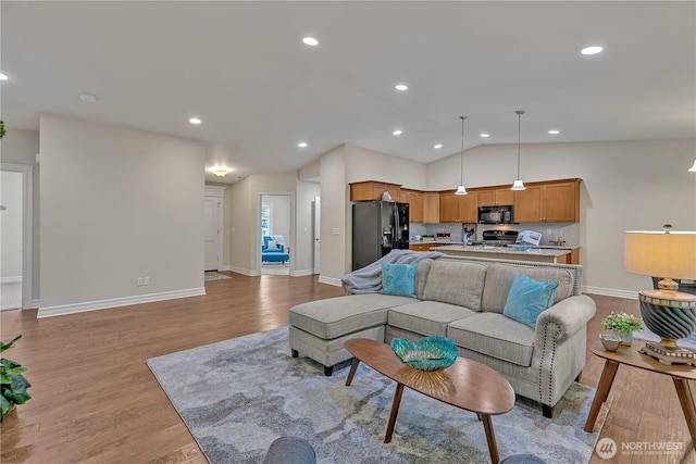 living area featuring lofted ceiling, recessed lighting, light wood-type flooring, and baseboards