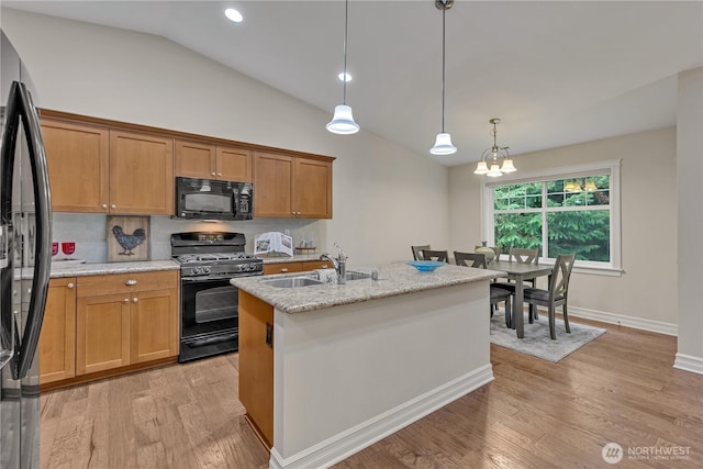 kitchen featuring a sink, lofted ceiling, black appliances, and light wood finished floors