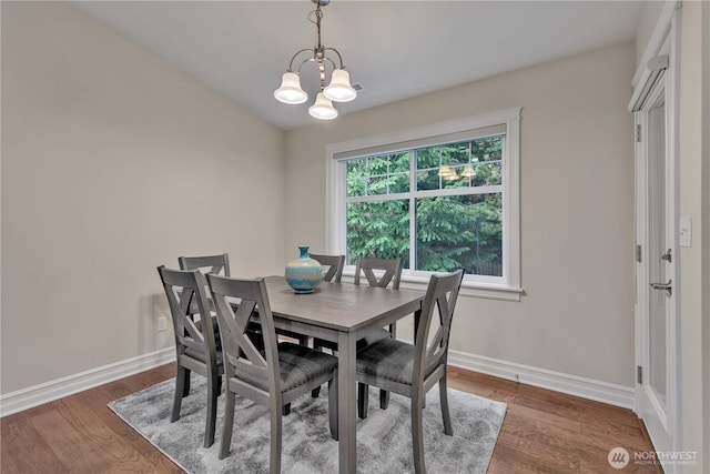 dining space featuring baseboards, dark wood-type flooring, and an inviting chandelier