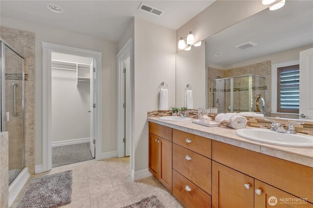 bathroom with a sink, visible vents, a stall shower, and a spacious closet