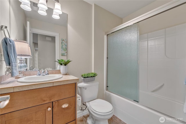 full bath featuring combined bath / shower with glass door, toilet, vanity, and baseboards