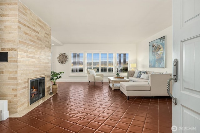 living room with dark tile patterned floors, a large fireplace, and baseboards